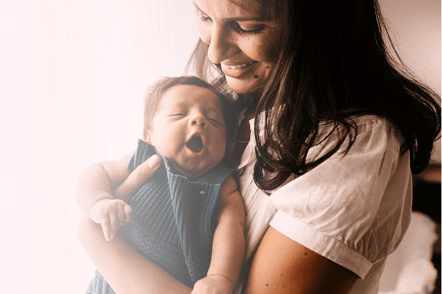 A woman holding a baby serious